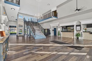 Tilava aula, jossa on keskeisellä paikalla sijaitseva portaikko, vastaanottotiski ja näkymä ulos.