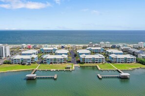 A coastal hotel with multiple blue buildings, a marina, and a view of the ocean. - Sea Oats J206 Large 2 bedroom 2 bath Pool,Waterfront,Beach access,Pet friendly (Gulf Shores)