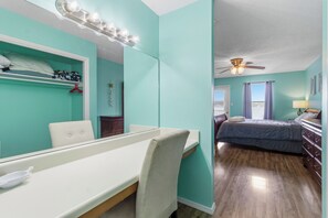 A bedroom with a bed, dresser, and a vanity with a mirror and lights. - Sea Oats J206 Large 2 bedroom 2 bath Pool,Waterfront,Beach access,Pet friendly (Gulf Shores)