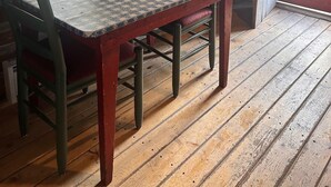 A wooden dining table with chairs, a patterned curtain, and a door leading outside. - Cabin #3 Cozy one room cabin in charming Gould, perfect for a getaway. (Walden)