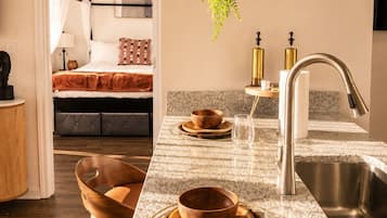 A modern kitchen with granite countertops, a stainless steel sink, and wooden bowls on the counter.