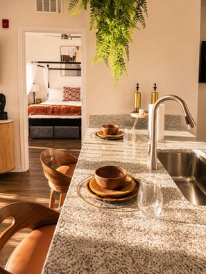A modern kitchen with granite countertops, a stainless steel sink, and wooden bowls on the counter.