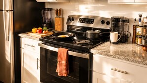 A modern kitchen with stainless steel appliances, white cabinetry, and a granite countertop. - King Bed + Saltwater Pool, 8 Min to Airport (Jacksonville)