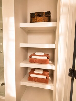 A storage unit with shelves containing folded towels and a wooden box.