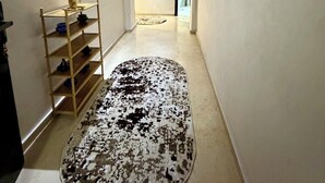 Ein Flur mit einem gemusterten Teppich, einem Regal mit Dekoration und einem gerahmten Bild an der Wand.