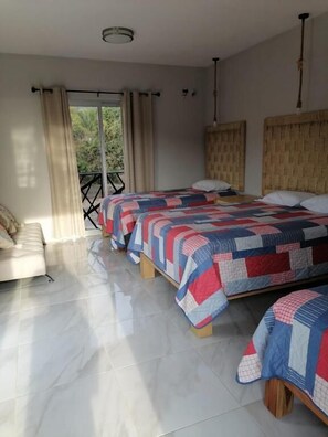Un dormitorio con dos camas, un sofá, un balcón y vistas al verdor.