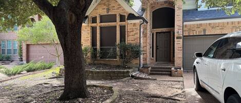 A residential house with a brick facade, a garage, and a driveway with a parked car.