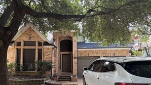 Il s’agit d’une propriété résidentielle comprenant une maison en briques, un garage et une voiture blanche garée devant.
