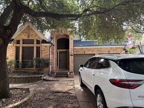Ein Wohnhaus mit Ziegelbau, Garage und einem weißen Auto davor.