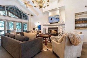A modern living room with a fireplace, large windows, and a ceiling fan. - Family Friendly Eagle Vail Retreat W/Hot Tub (Avon)