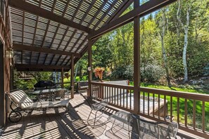 Eine überdachte Terrasse im Freien mit Sitzgelegenheiten und Blick auf einen bewaldeten Bereich.