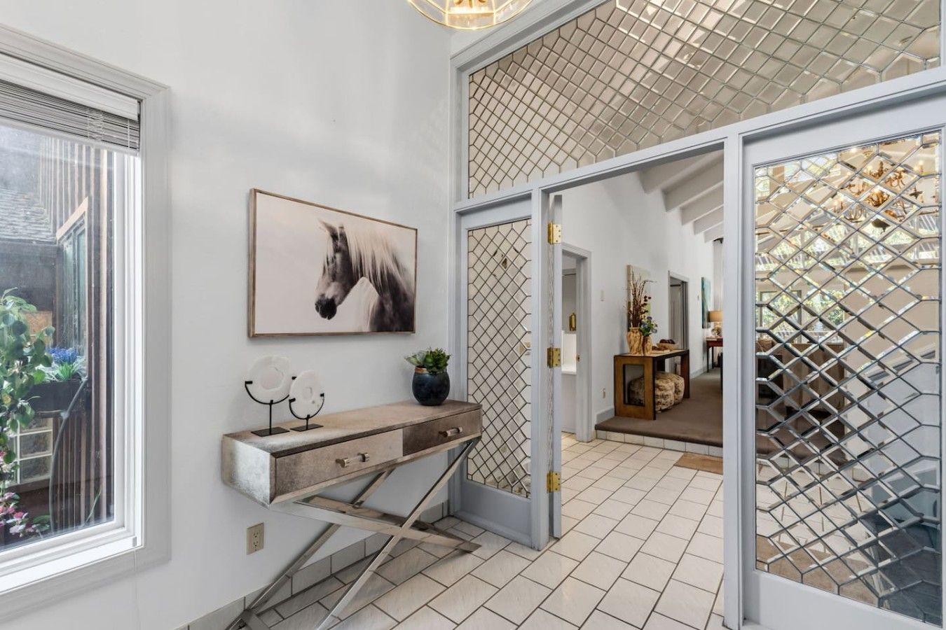 A hallway with a wooden console table, a framed horse painting, and a staircase leading to another room.