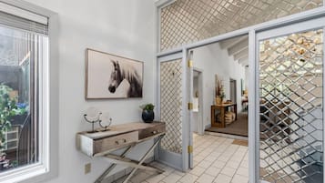 A hallway with a wooden console table, a framed horse painting, and a staircase leading to another room.