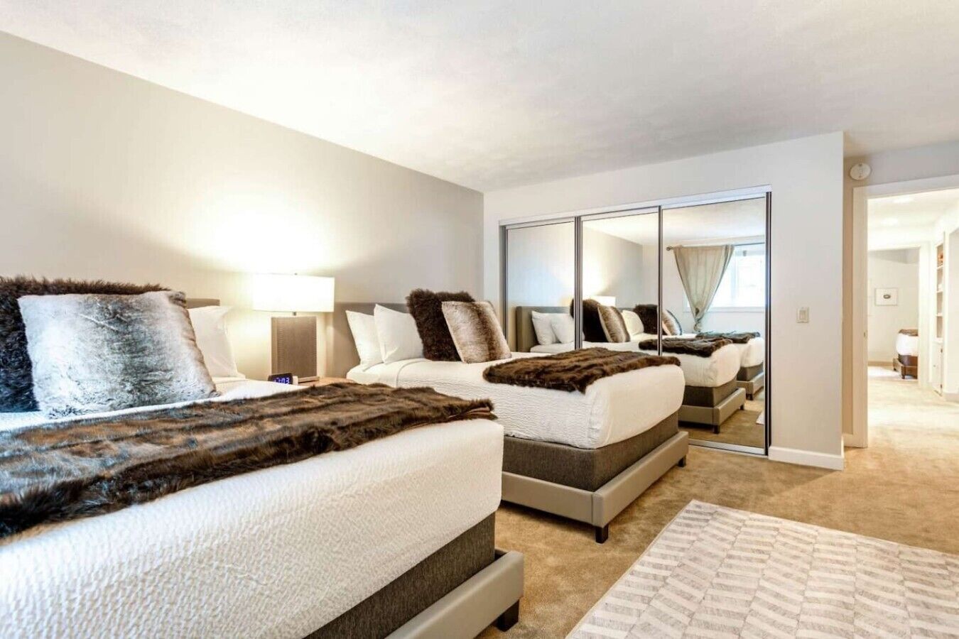 Un dormitorio con dos camas, un espejo grande y suelo alfombrado.