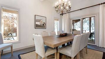 A dining room with a large table, chairs, a chandelier, and a picture on the wall.