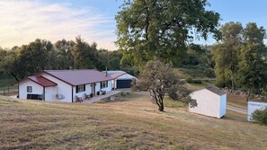 A white building with a red roof, a garage, and a small shed. -  Monte Mariposa Casita:Near Yosemite,3 Private Acres,King Suite,2 Fire Pits (Mariposa)
