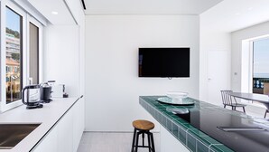 A modern kitchen with a large window, a flat-screen TV, and a bar area. - Magnificent apartment (Nice)
