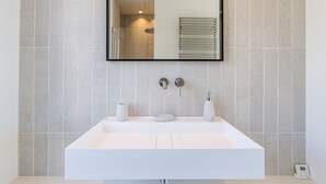 A bathroom with a white sink, two faucets, a mirror, and a towel rack. - Magnificent apartment (Nice)