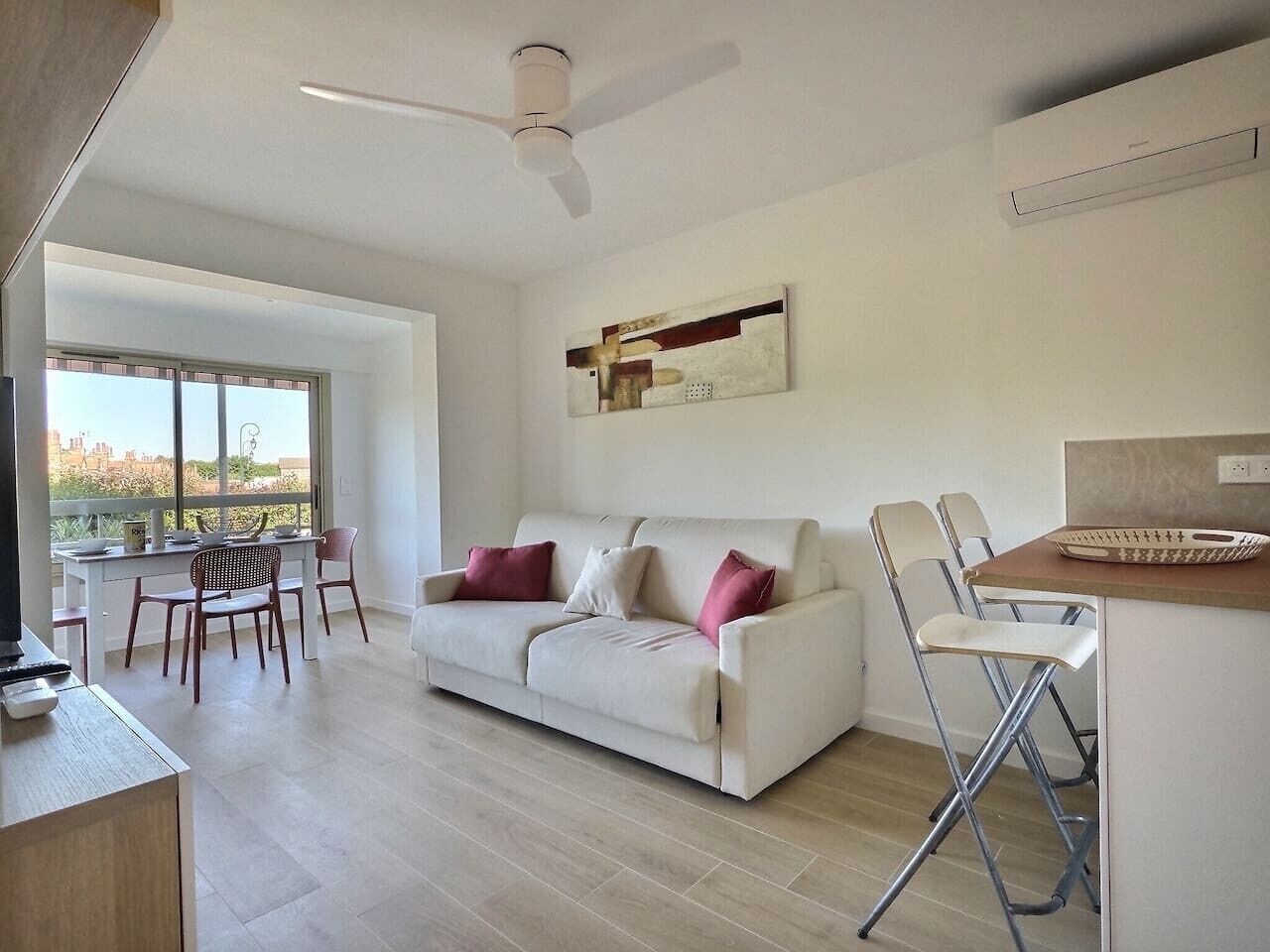 A modern living room with a sofa, chairs, a dining table, and a large window.
