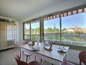 Ein Essbereich mit Tisch, Stühlen und Blick durch große Fenster.