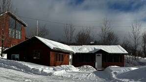 Paisaje nevado con dos cabañas de madera y un edificio moderno al fondo.