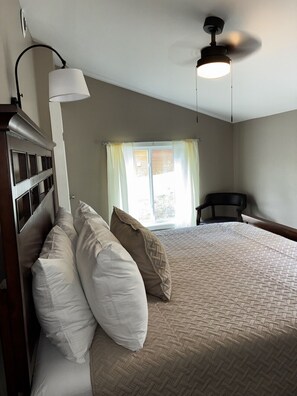 A bedroom with a bed, pillows, a ceiling fan, a window with curtains, and a chair. - Killington / Rutland   2 Bdrm Cabin w/ Mtn view (Mendon)