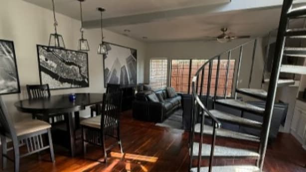 Uma sala de estar ampla com uma mesa de jantar, sofás e um lance de escadas.