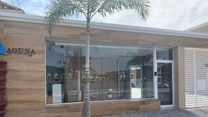 Un edificio moderno con fachada de madera, entrada de cristal y una palmera frente a él.