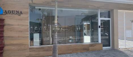 A modern building with a wooden facade, a glass entrance, and a palm tree in front.