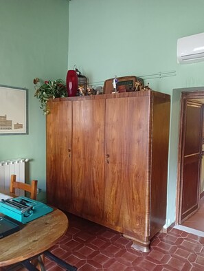 A wooden cabinet with decorative items, a radiator, a table with a blue object, and a door. - Florentine Renaissance, to experience authentic Florence in the heart of the city (Firenze)