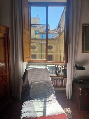 A room with a bed, a window with curtains, a bookshelf, and a desk with a lamp. - Florentine Renaissance, to experience authentic Florence in the heart of the city (Firenze)