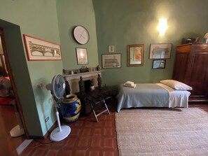 A room with a bed, a fan, a fireplace, and various framed pictures on the wall. - Florentine Renaissance, to experience authentic Florence in the heart of the city (Firenze)
