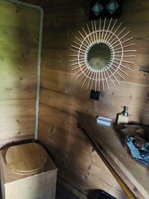 Un interior de madera con una cuerda, un adorno circular de madera en la pared, una caja de madera pequeña y un banco de madera.
