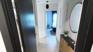 A hallway with a black door, a mirror, a plant, and a bed in the distance. - Luxury, modern, and cozy apartment just 5 minutes from the Baillargues Golf Course  (Baillargues)