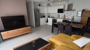 A modern living room with a sofa, a TV, and a dining area with chairs and a table. - Luxury, modern, and cozy apartment just 5 minutes from the Baillargues Golf Course  (Baillargues)