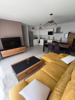 Ein modernes Wohnzimmer mit einer Couch, einem Fernseher und einem Essbereich mit Stühlen und einem Tisch.