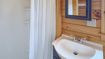 Une salle de bain avec une baignoire, un rideau de douche, un lavabo et un miroir.