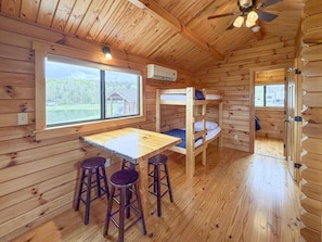 A cabin with bunk beds, a table, and bar stools.