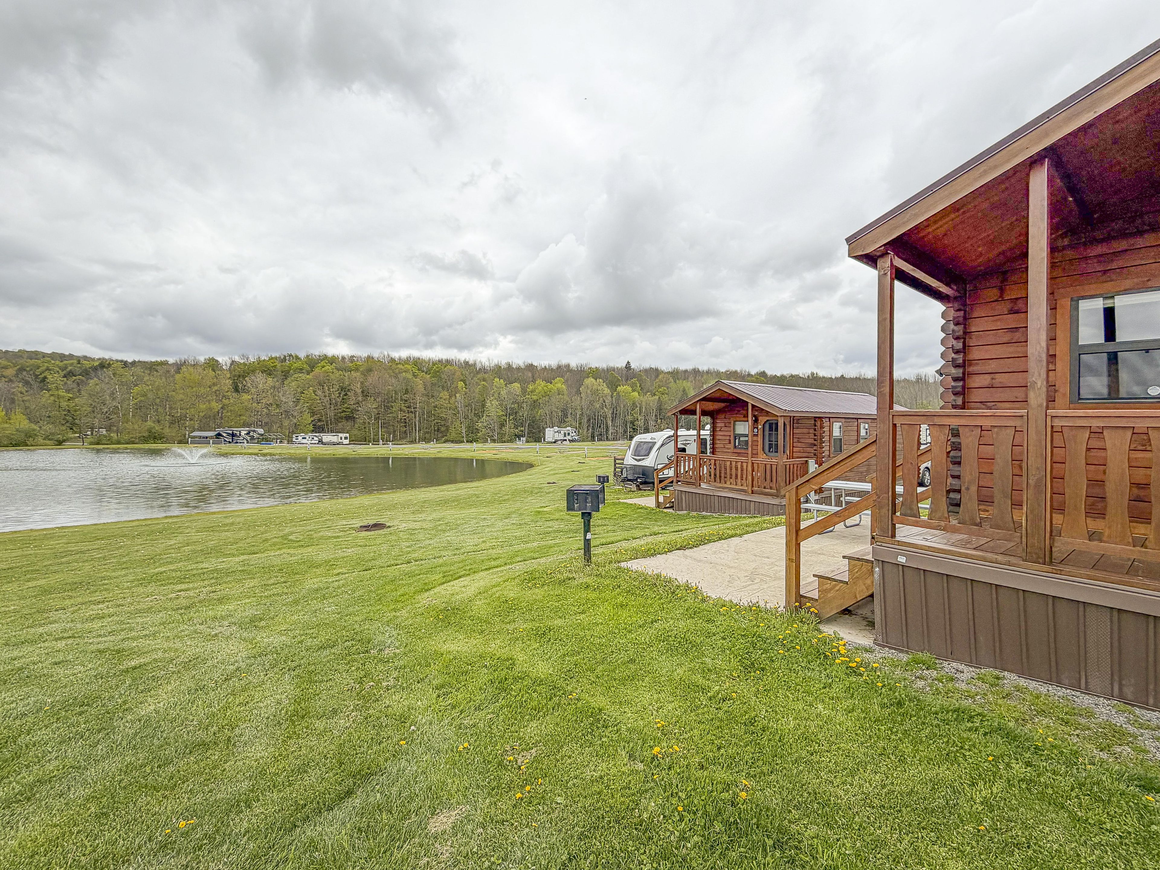 A lakeside cabin with a deck, a picnic table, and a view of the lake and forest.