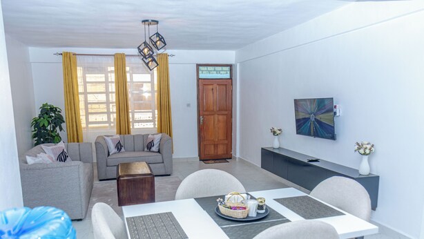 Un salon moderne avec un canapé, une table à manger et des chaises, une porte en bois et un tableau accroché au mur.