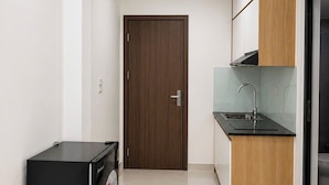 A compact kitchen with a refrigerator, a sink, and wooden cabinets. - Dreamora Serenity Hotel & Residence (Hanoi)
