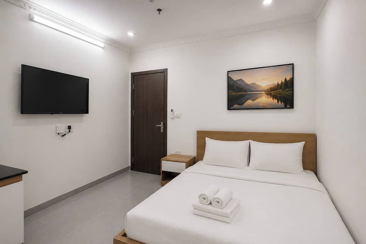Une chambre d’hôtel avec un lit, une télévision, un tableau et une porte.
