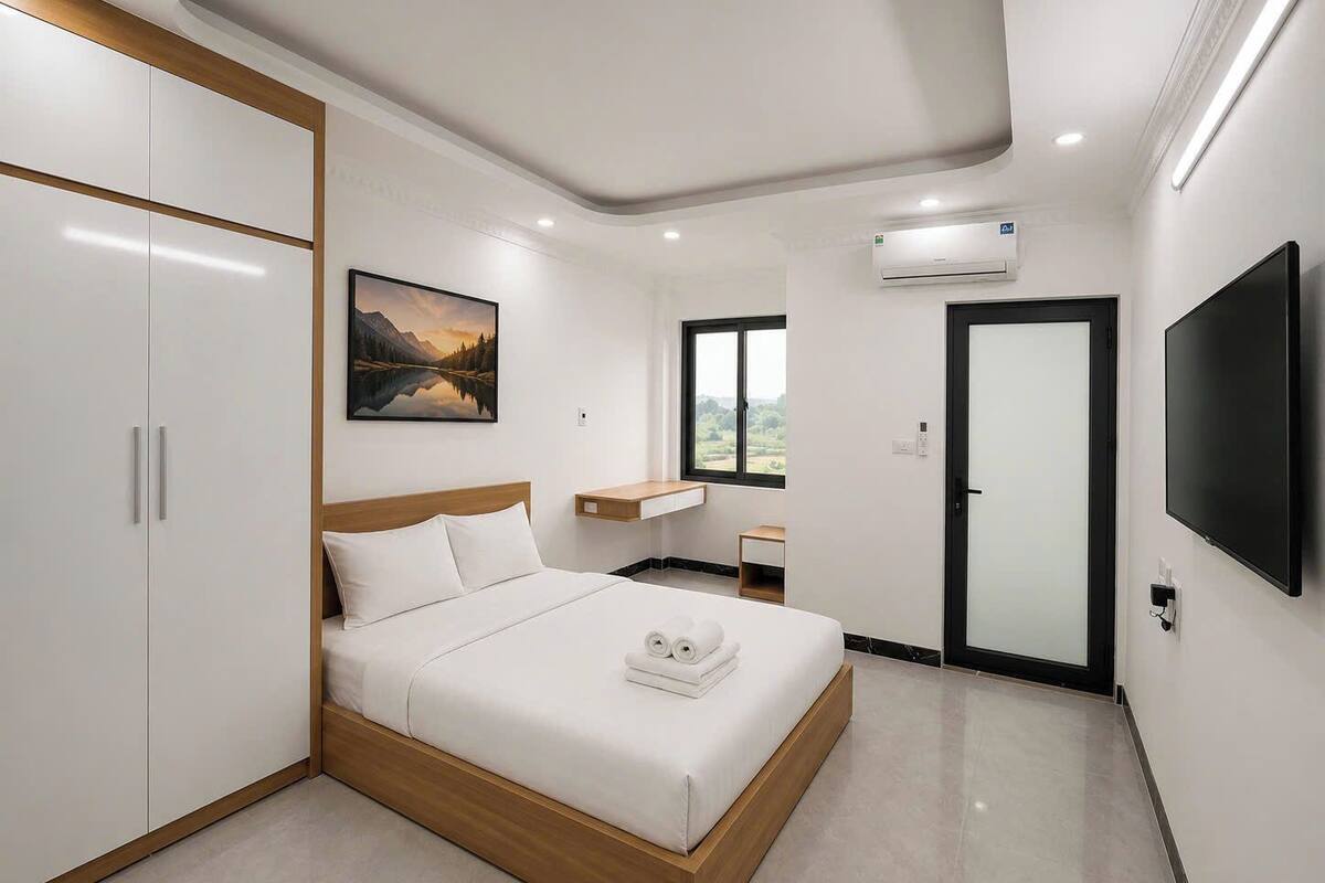 Une chambre d’hôtel moderne équipée d’un lit, d’une armoire, d’une télévision et d’un tableau.