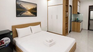 A modern bedroom with a bed, a wardrobe, a small kitchenette, and a painting on the wall. - Dreamora Serenity Hotel & Residence (Hanoi)