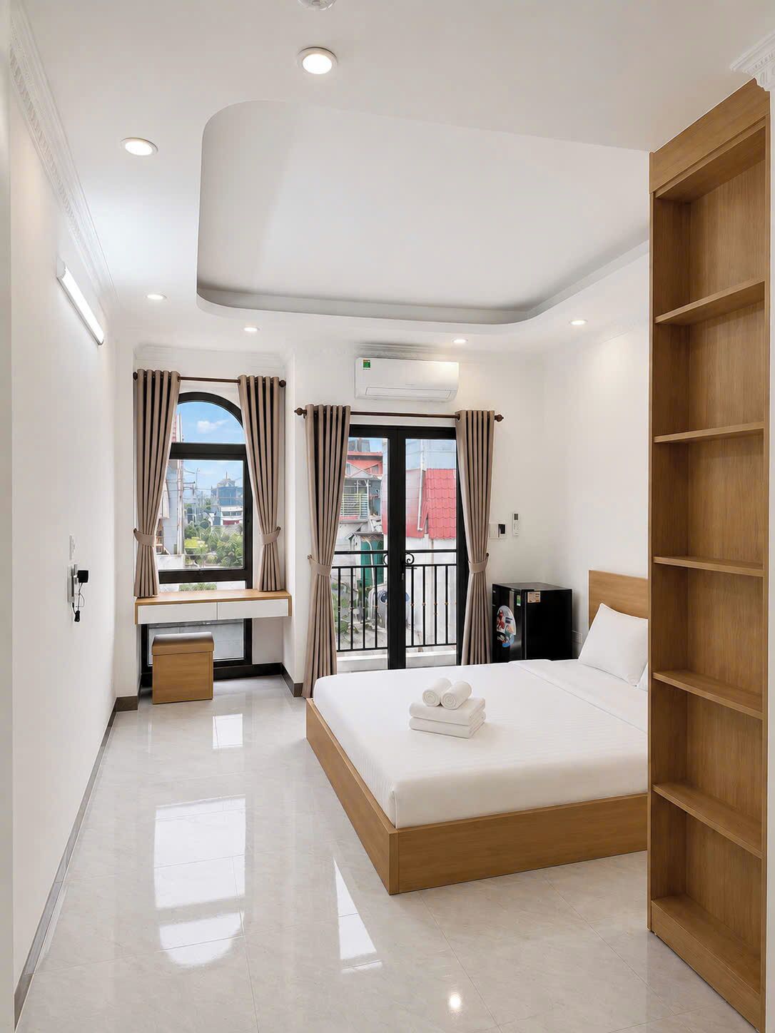A modern hotel room with a bed, a desk, a wardrobe, and a balcony with curtains.