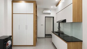 A modern kitchen with white cabinets, a black countertop, and a built-in stove. - Dreamora Serenity Hotel & Residence (Hanoi)