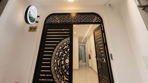 A modern building with a central staircase, a decorative black gate, and a fire extinguisher. - Dreamora Serenity Hotel & Residence (Hanoi)