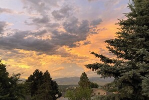 Una casa con montañas al fondo y un cielo nublado.