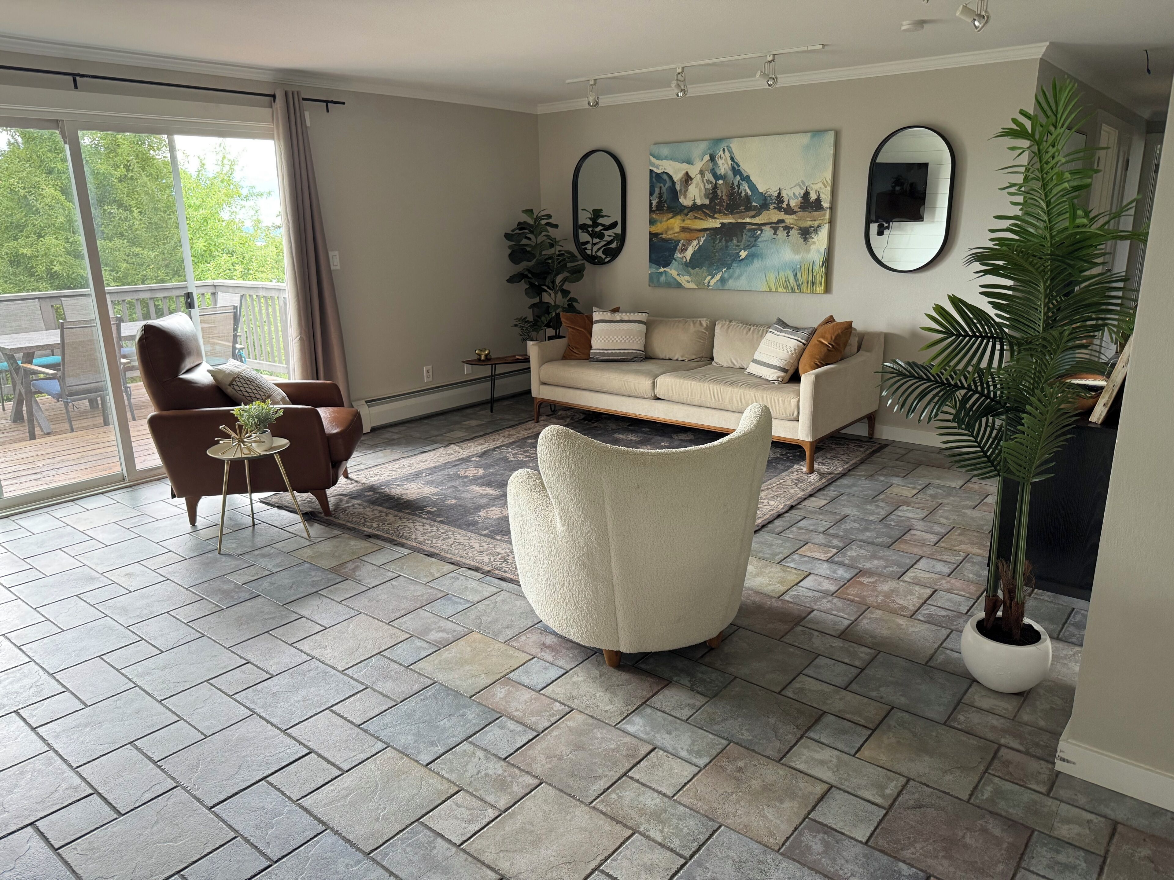Un salon avec un canapé, un fauteuil et une plante en pot.