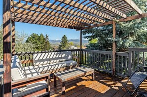 A wooden deck with a pergola, a bench, and a chair.
